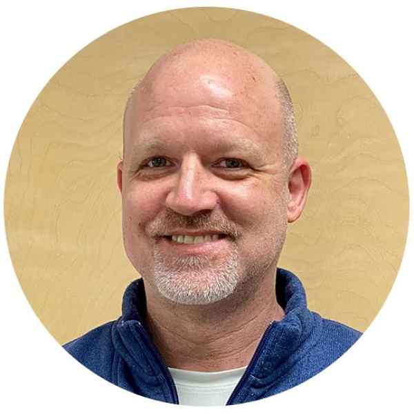 Smiling man with a bald head and goatee, wearing a blue jacket.